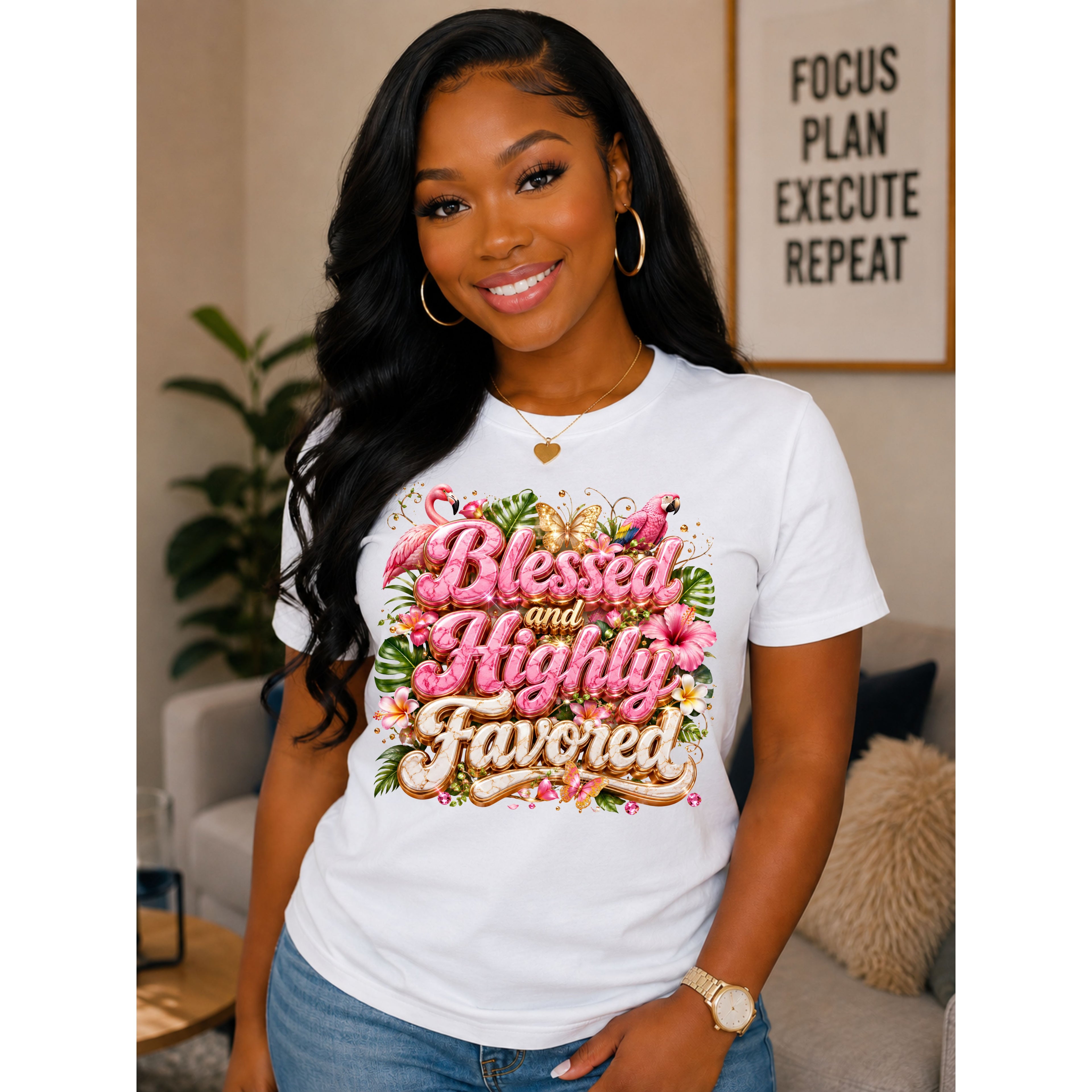 A woman wearing a white graphic t-shirt with a colorful floral design that reads 'Blessed and Highly Favored' in pink and gold lettering, posed in a cozy living room setting.