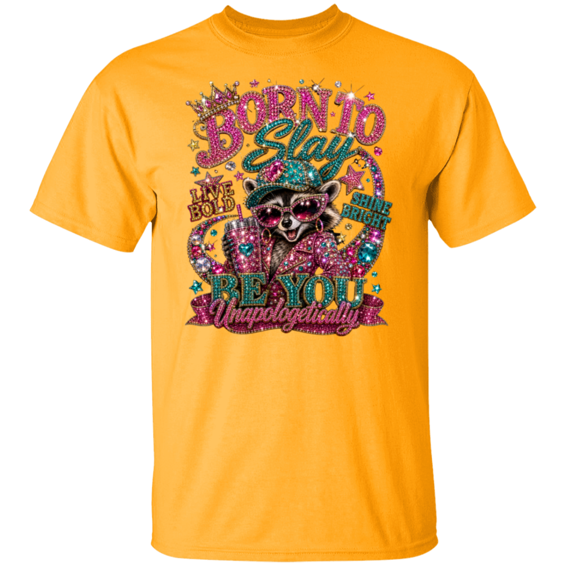 A gold color short-sleeve crewneck t-shirt featuring a large, colorful graphic on the front. The graphic depicts a raccoon wearing sunglasses and a hat, surrounded by glittery text that reads 'BORN TO BE YOU Unapologetically' and 'HAVE BOLD BE YOU'.