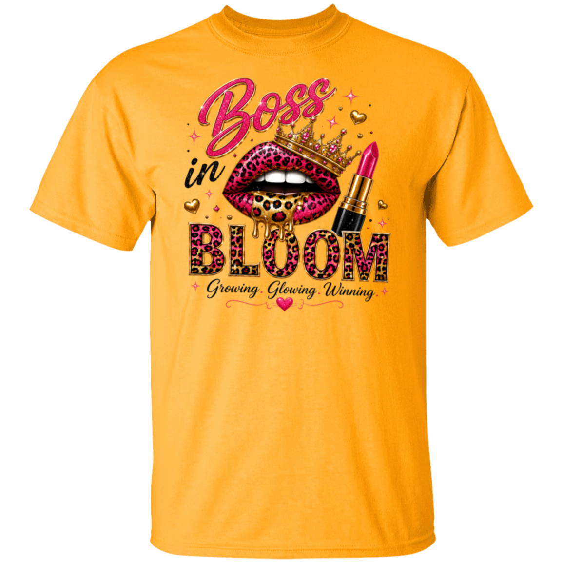 A gold color short-sleeve t-shirt with a graphic print on the front. The graphic features a pair of leopard-print lips wearing a gold crown, a pink lipstick tube, and the text 'Boss in BLOOM' with 'Growing, Glowing, Winning' underneath.