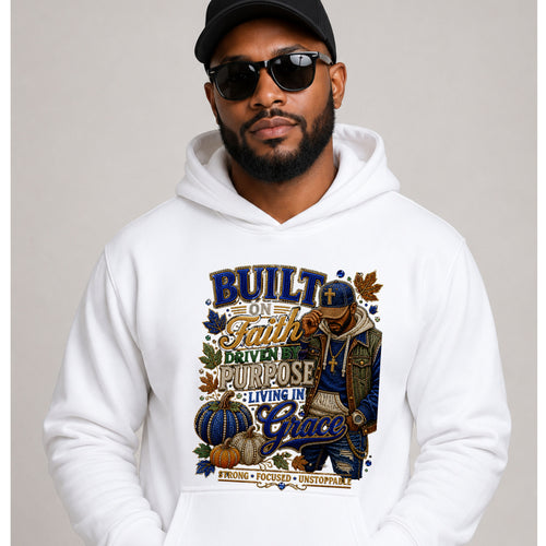 A man wearing a white pullover hoodie with a large autumn-themed graphic print that reads 'Built on Faith, Powered by Purpose, Living in Grace' and features pumpkins, leaves, and a person in a cap. He is also wearing a black cap and sunglasses against a plain light gray studio background.