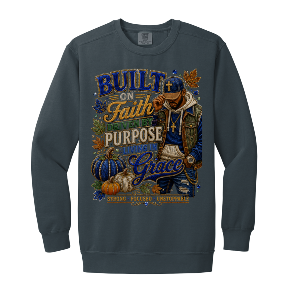 A denim color crewneck sweatshirt featuring a large, detailed graphic print on the front. The graphic displays a man in a blue cap and jacket with gold chains, surrounded by pumpkins, autumn leaves, and text that reads 'BUILT ON Faith, DESIGNED by PURPOSE, DRIVEN by Grace, STRONG FOCUSED, UNSTOPPABLE'.