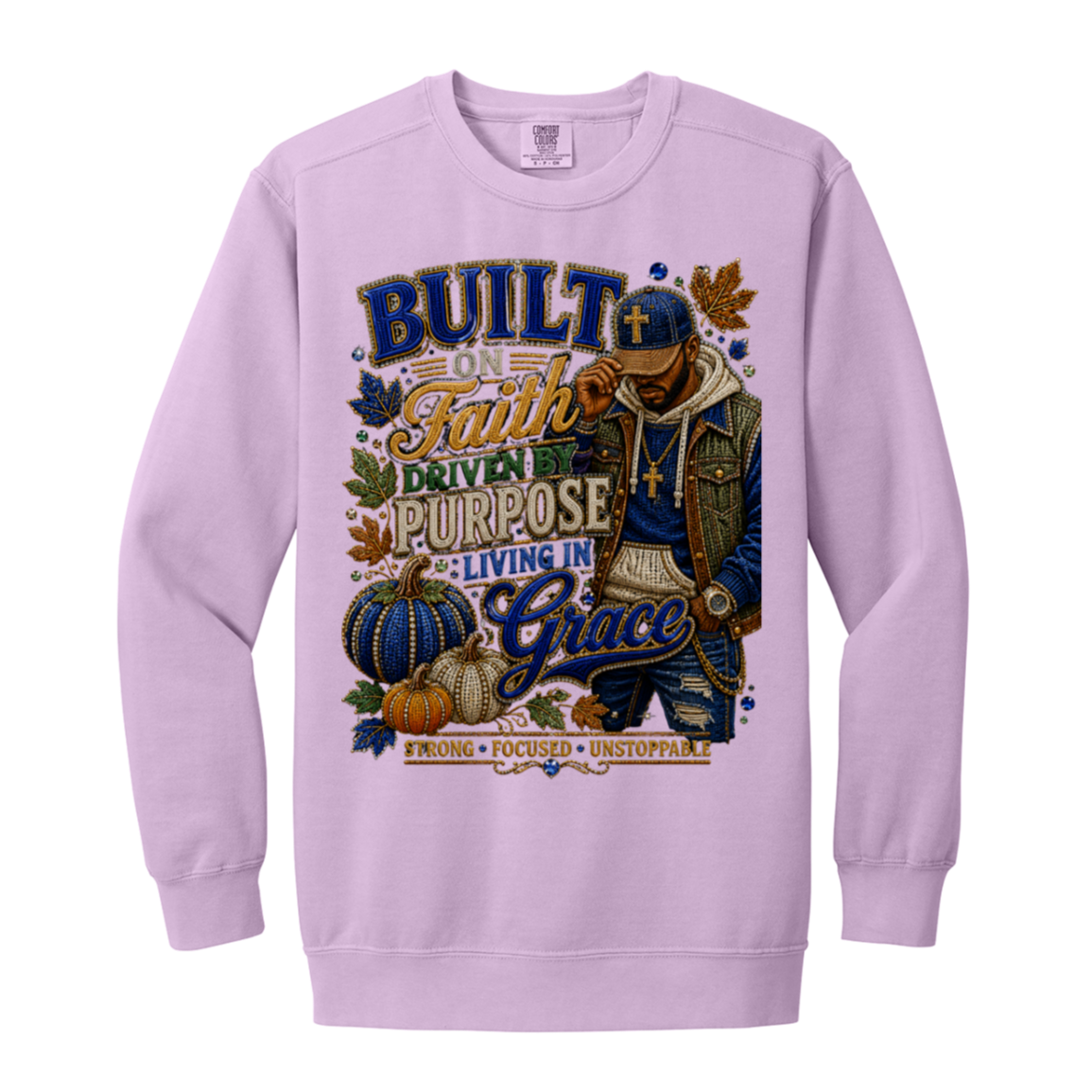 An orchid color crewneck sweatshirt featuring a large graphic print on the front. The graphic depicts a man in a blue cap and jacket with a cross necklace, surrounded by pumpkins, autumn leaves, and text that reads 'BUILT ON Faith DRIVEN PURPOSE LIVING IN Grace' and 'STRONG FOCUSED UNSTOPPABLE'.