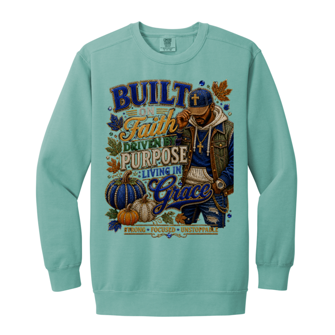 A seafoam color crewneck sweatshirt featuring a large graphic print on the front. The graphic displays a man wearing a cap and sunglasses, surrounded by pumpkins, autumn leaves, and text that reads 'BUILT ON Faith DRIVEN PURPOSE LIVING IN Grace'.