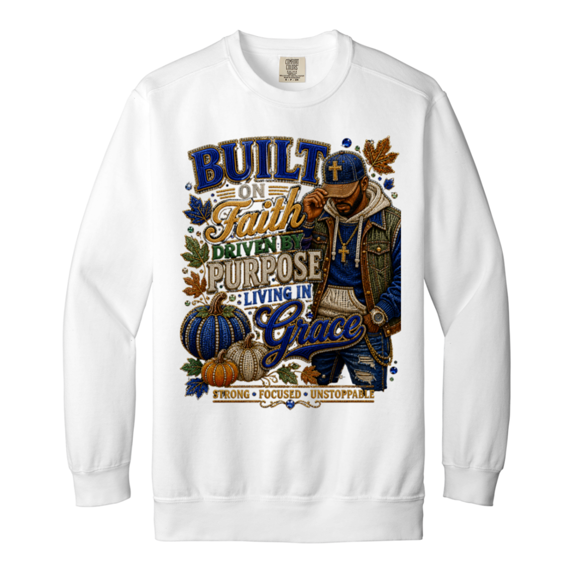 A white color crewneck sweatshirt featuring a large, detailed graphic print on the front. The graphic displays a male figure in a blue cap and jacket, surrounded by pumpkins, autumn leaves, and text that reads 'BUILT ON Faith DRIVEN PURPOSE LIVING IN Grace STRONG FOCUSED UNSTOPPABLE'.