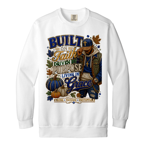 A white color crewneck sweatshirt featuring a large, detailed graphic print on the front. The graphic displays a male figure in a blue cap and jacket, surrounded by pumpkins, autumn leaves, and text that reads 'BUILT ON Faith DRIVEN PURPOSE LIVING IN Grace STRONG FOCUSED UNSTOPPABLE'.