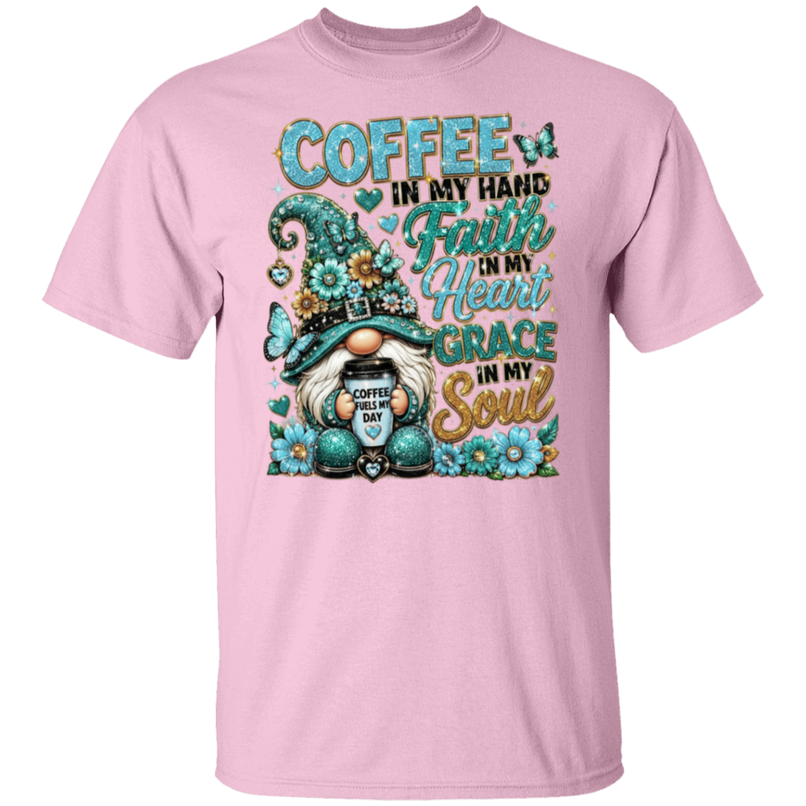 A light pink short-sleeve crewneck t-shirt featuring a colorful graphic print of a gnome holding a coffee mug, surrounded by flowers and the text 'COFFEE IN MY HAND Faith IN My Heart GRACE IN My Soul'.