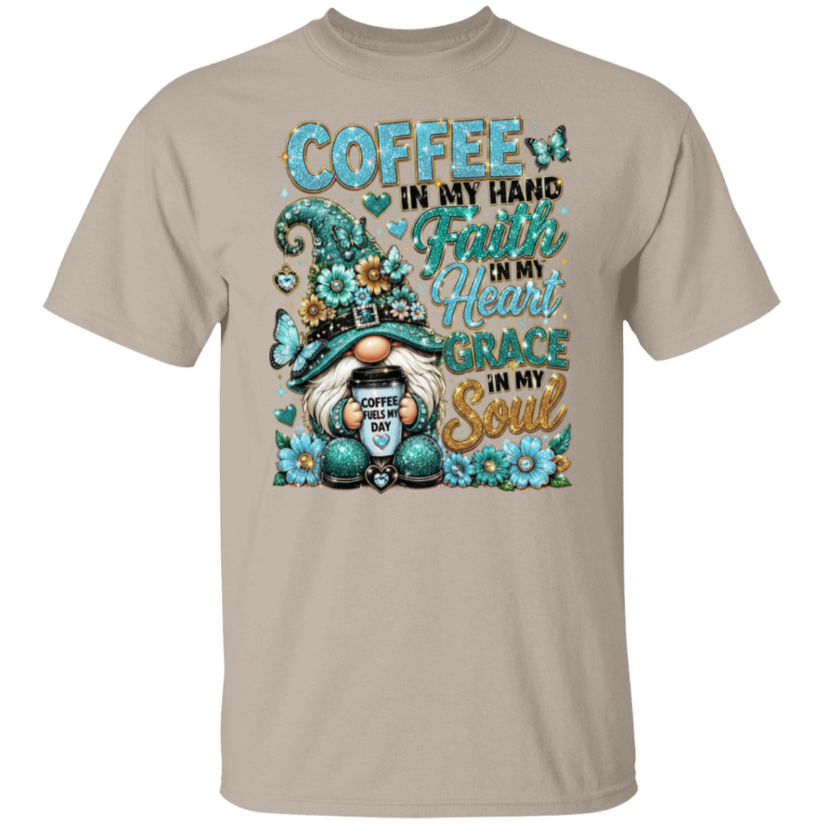 A sand crewneck t-shirt featuring a colorful graphic print of a gnome holding a coffee mug, surrounded by flowers and butterflies, with the text 'COFFEE IN MY HAND Faith IN My Heart GRACE IN My Soul'.