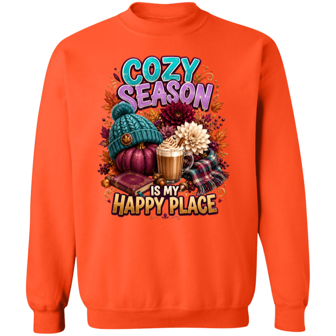 An orange crewneck sweatshirt featuring a colorful graphic print on the front with the text 'COZY SEASON IS MY HAPPY PLACE' and illustrations of a teal knit beanie, a purple pumpkin, a hot cocoa mug, and autumn flowers.