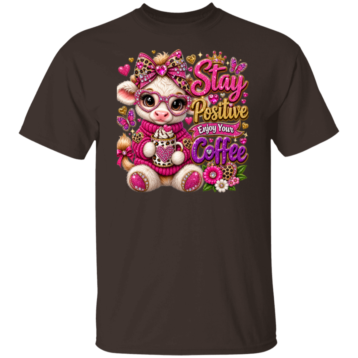 A dark chocolate short-sleeve crewneck t-shirt featuring a colorful graphic print of a cartoon cow wearing pink glasses and a pink sweater, surrounded by flowers, butterflies, and the text 'Stay Positive Enjoy Your Coffee'.