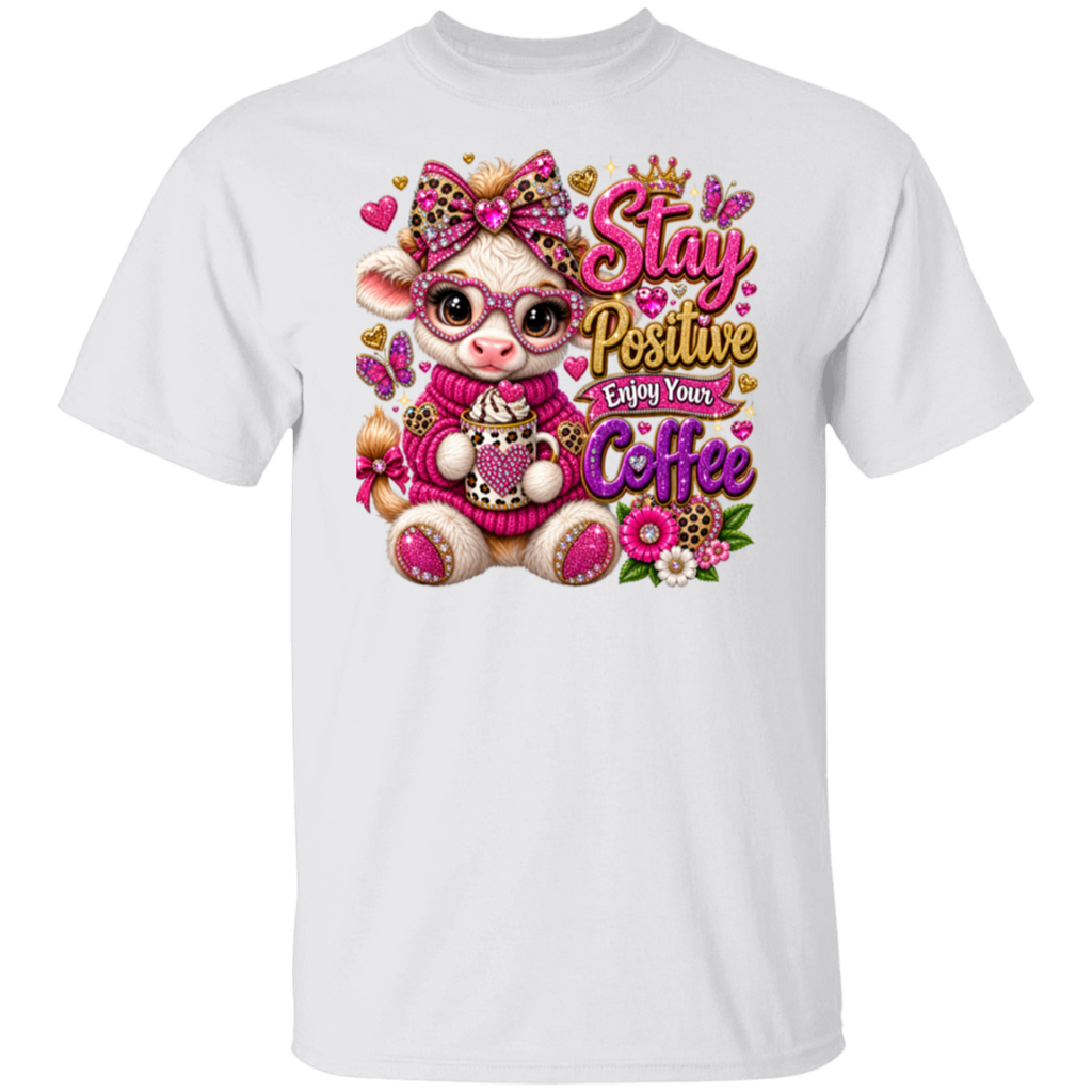 A white short-sleeve crewneck t-shirt featuring a colorful graphic print of a cute cartoon cow wearing pink glasses and a pink sweater, surrounded by flowers and butterflies, with the text 'Stay Positive Enjoy Your Coffee'.