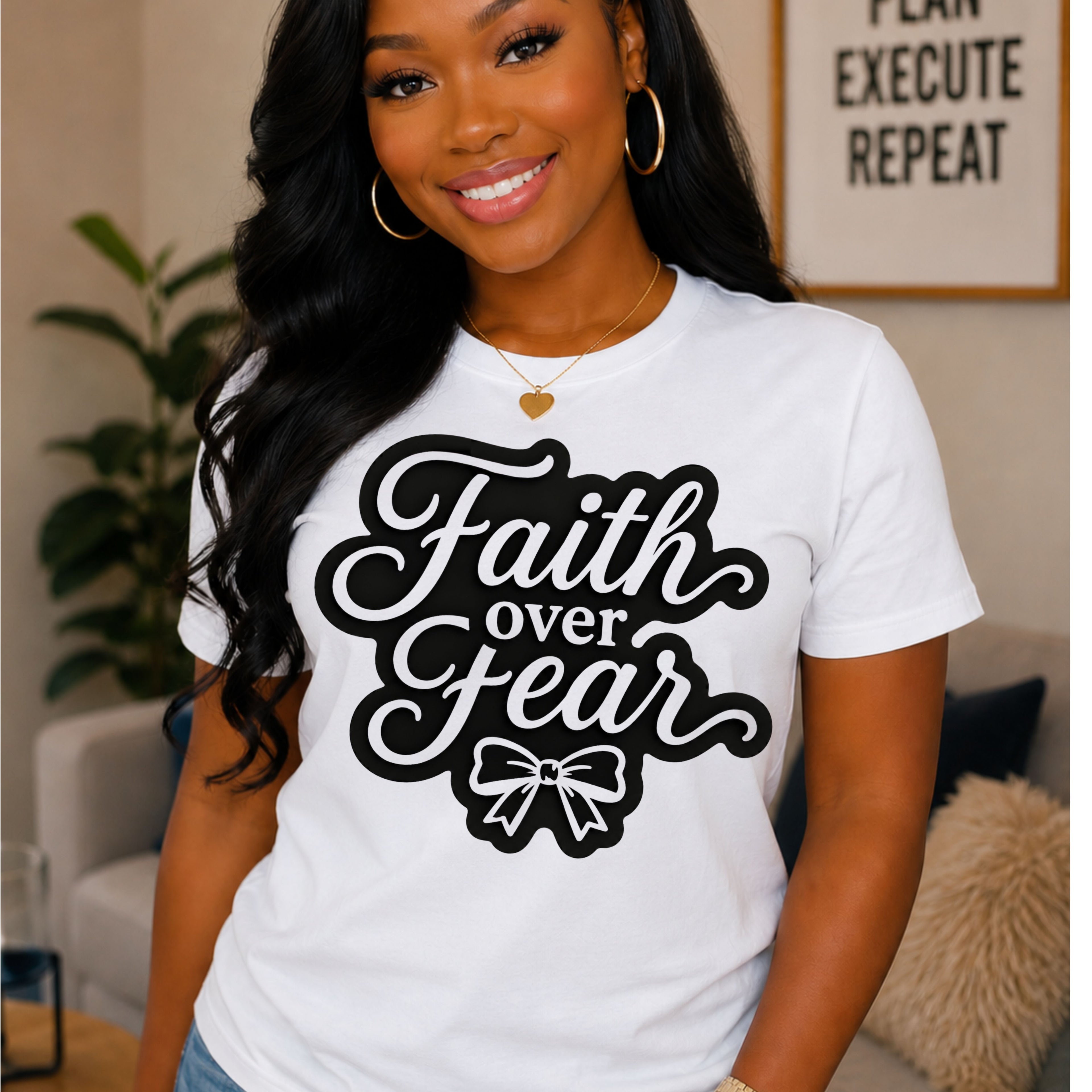 A woman wearing a white short-sleeve t-shirt with a black graphic that reads 'Faith over Fear' and a bow illustration, posed in a cozy indoor setting.