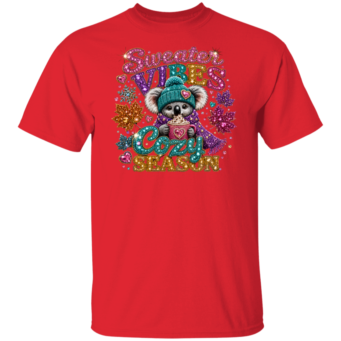 A red short-sleeve crewneck t-shirt featuring a colorful graphic print of a cute koala wearing a teal beanie and holding a mug, surrounded by glittery text that reads 'Sweeter VIBES Cozy SEASON' and holiday-themed embellishments.