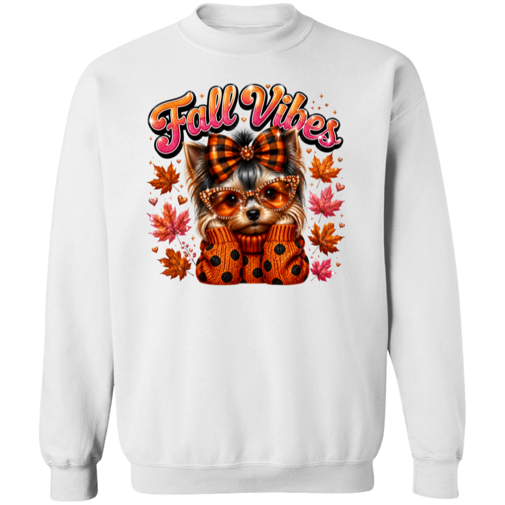 A white crewneck sweatshirt featuring a colorful graphic of a small dog wearing an orange plaid bow and polka-dot sweater, surrounded by autumn leaves, with the text 'Fall Vibes' in orange and pink.