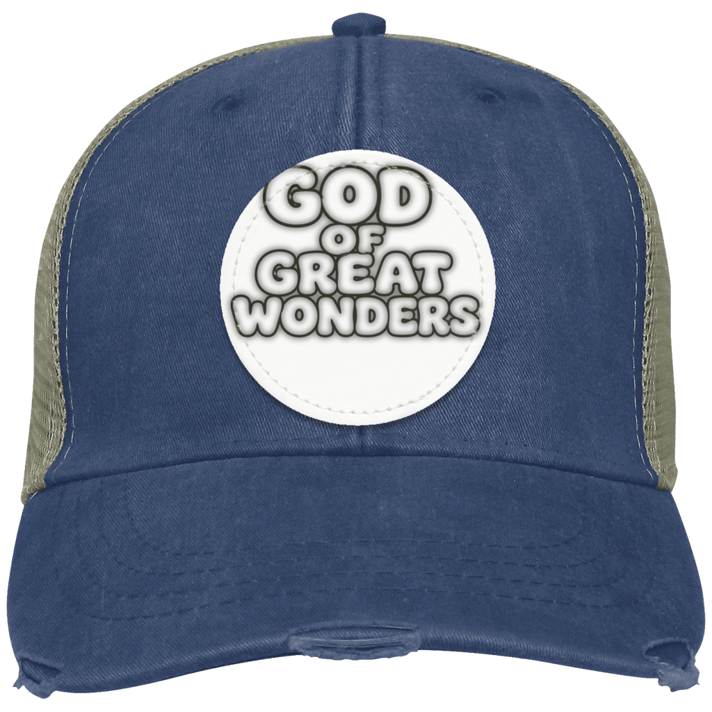 A distressed trucker hat in navy blue with forest mesh side panels and a white circular patch on the front that reads 'GOD OF GREAT WONDERS'.
