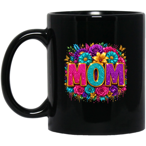 A glossy black ceramic mug featuring a vibrant, colorful graphic on the side. The graphic displays the word 'MOM' in glittery pink and purple letters, surrounded by a dense border of multicolored flowers including pink, blue, yellow, and purple, with a dripping paint effect at the bottom.