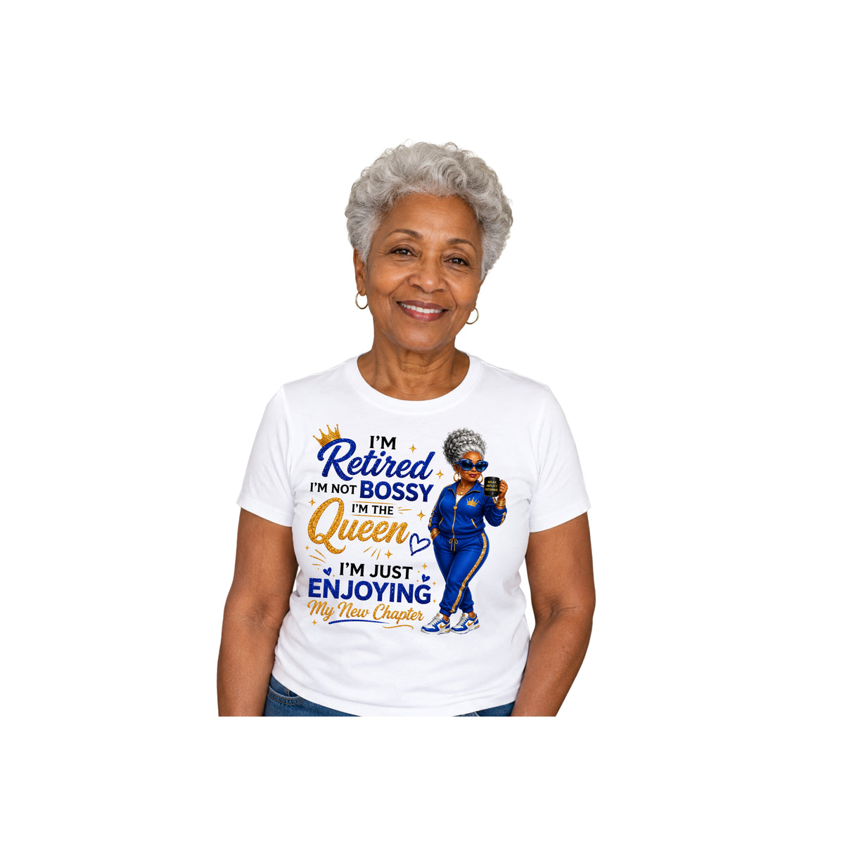 An older woman with short gray hair is shown from the waist up wearing a white graphic T-shirt. The shirt features a blue and orange print with the text 'I'm Retired I'm Not Bossy In The Queen I'm Just Enjoying My New Chapter' and an illustration of a woman in a blue outfit.