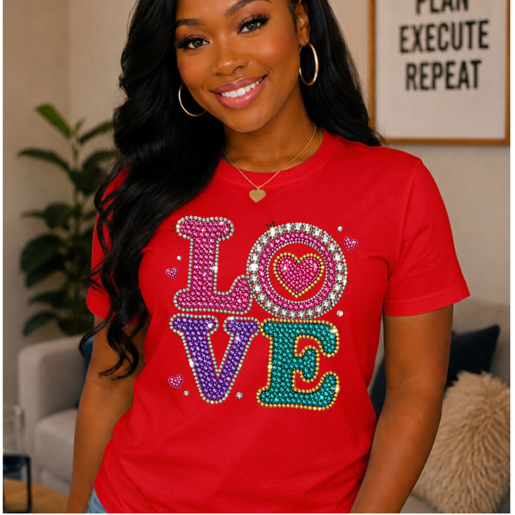 A woman wearing red color short-sleeve crewneck t-shirt featuring a large, colorful rhinestone-style 'LOVE' graphic on the chest, displayed against a solid white background.