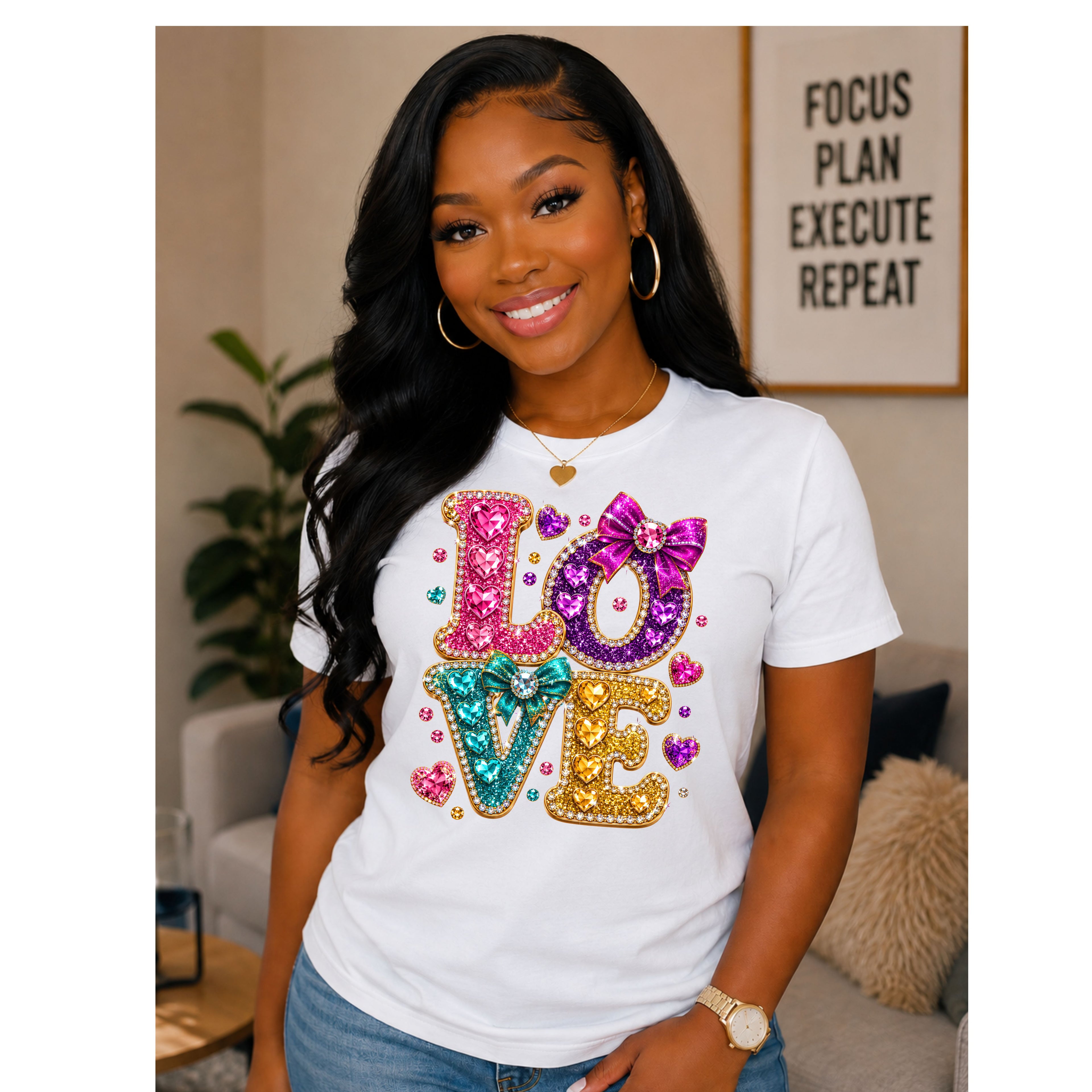 A woman wearing a white crewneck t-shirt with a colorful, glittery 'LOVE' graphic on the front, posed in a cozy living room setting.