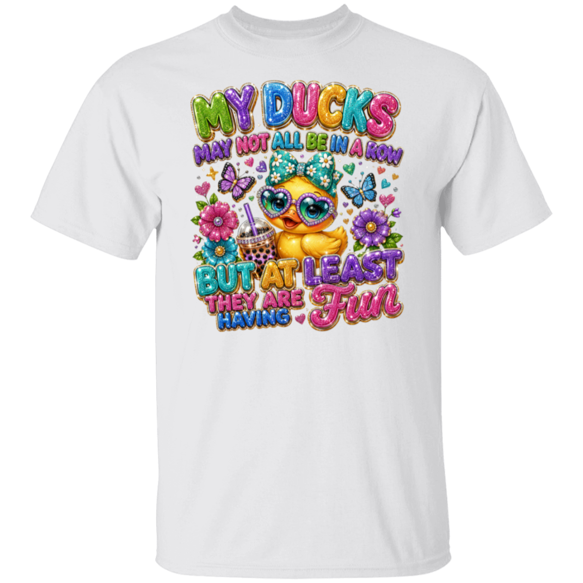 A white short-sleeve crewneck t-shirt featuring a colorful graphic print on the front. The graphic shows a cute cartoon duck wearing sunglasses and a party hat, surrounded by flowers, butterflies, and the text 'MY DUCKS MAY NOT ALL BE IN A ROW BUT AT LEAST THEY ARE HAVING Fun'.