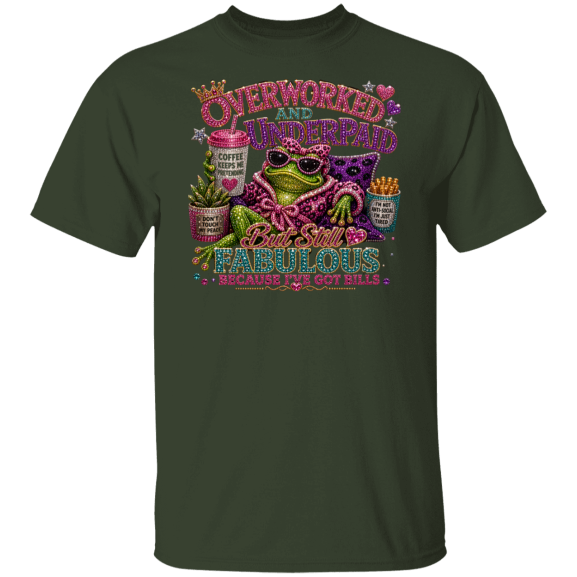 A dark forest green short-sleeve t-shirt with a colorful graphic print on the front. The graphic features a green frog wearing sunglasses and a pink leopard-print shirt, surrounded by text that reads 'OVERWORKED AND UNDERPAID' and 'But still FABULOUS BECAUSE I'D GOT BILLS'.