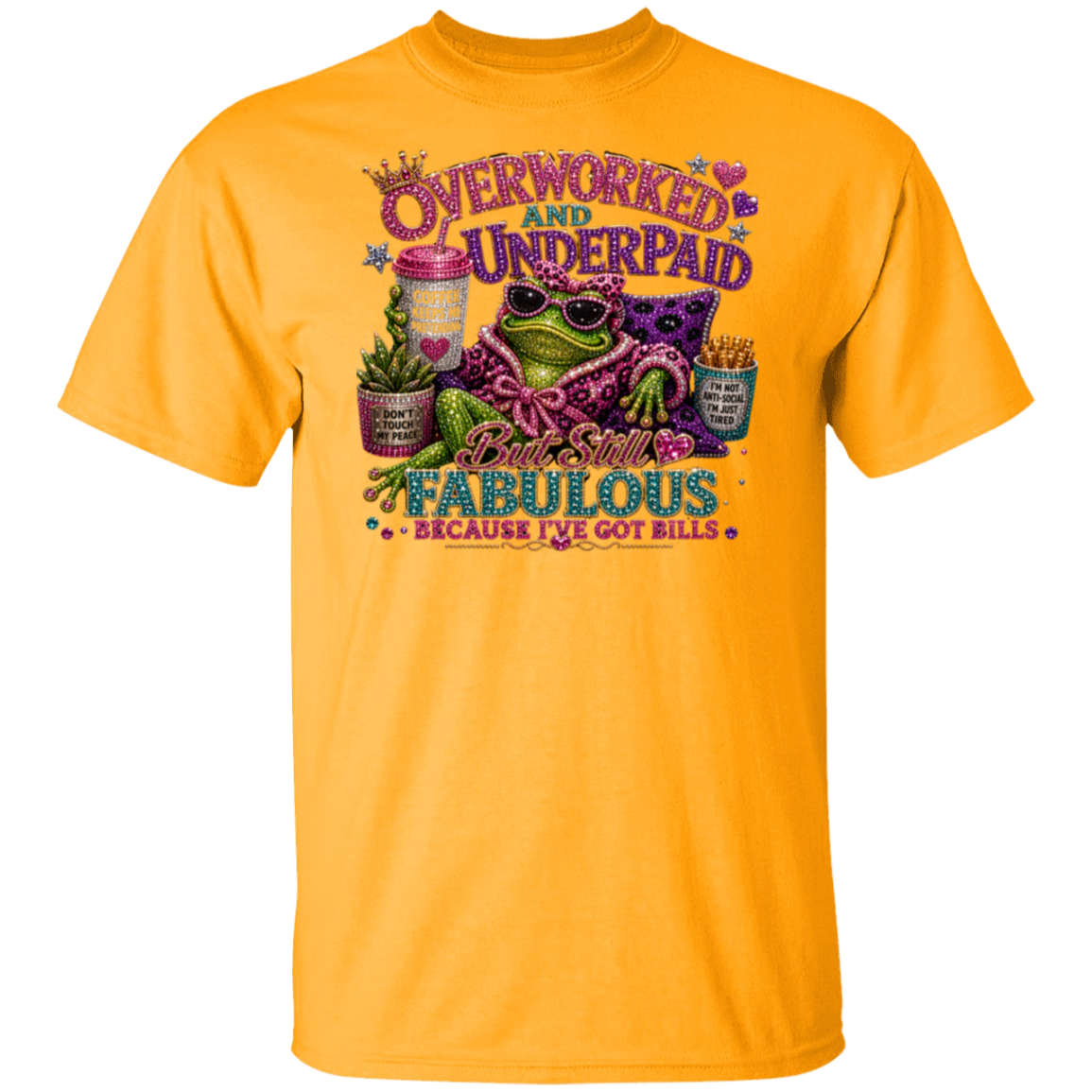 A gold short-sleeve t-shirt with a colorful graphic print on the front. The graphic features a frog wearing sunglasses and a purple patterned shirt, surrounded by text that reads 'Overworked and Underpaid' and 'But Still Fabulous Because I've Got Bills'.