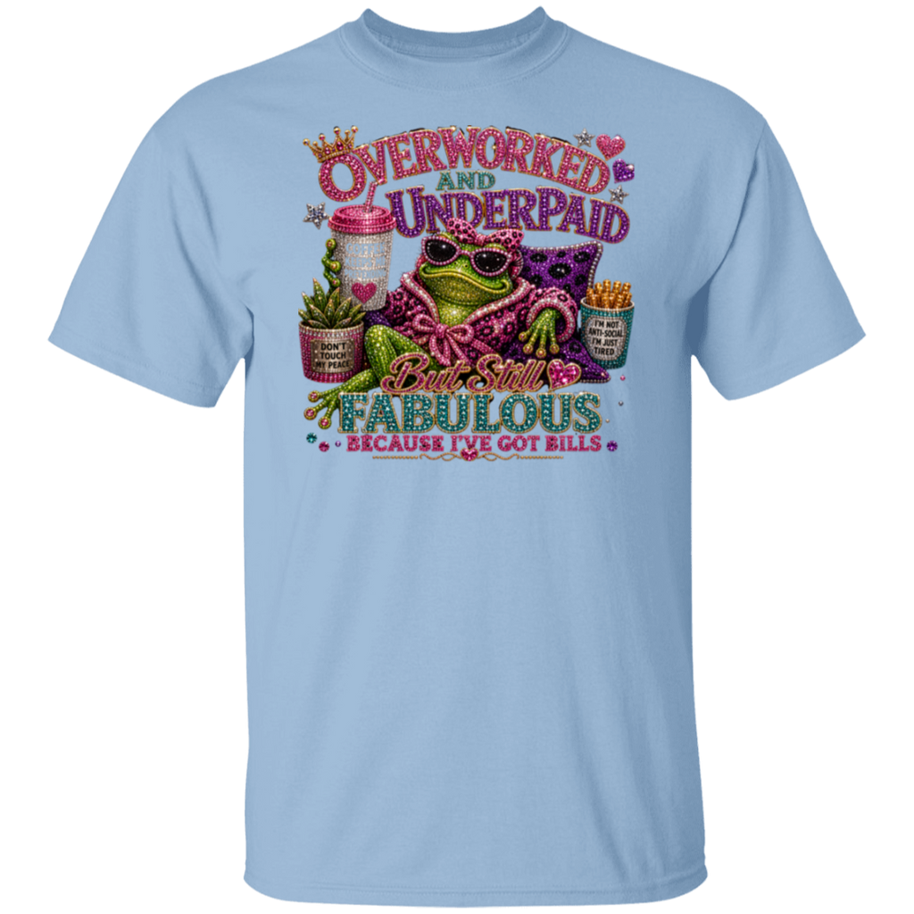 A light blue crewneck t-shirt featuring a colorful graphic print of a frog wearing sunglasses and a pink patterned shirt, surrounded by text that reads 'Overworked and Underpaid But Still Fabulous Because I've Got Bills'.