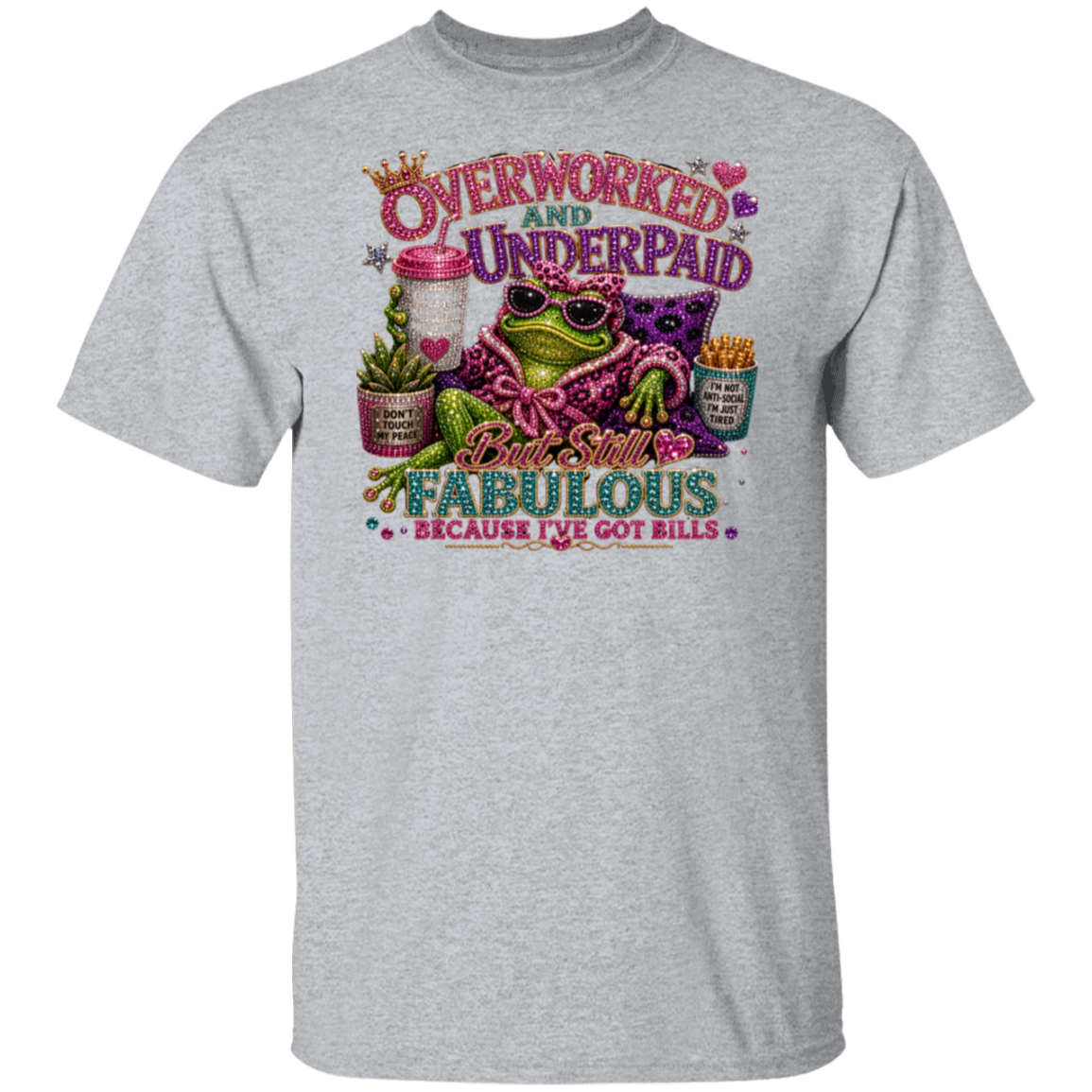 A sport grey short-sleeve crewneck t-shirt featuring a colorful graphic print of a frog wearing sunglasses and a pink patterned shirt, surrounded by text that reads 'Overworked and Underpaid' and 'But Still Fabulous Because I've Got Bills'.