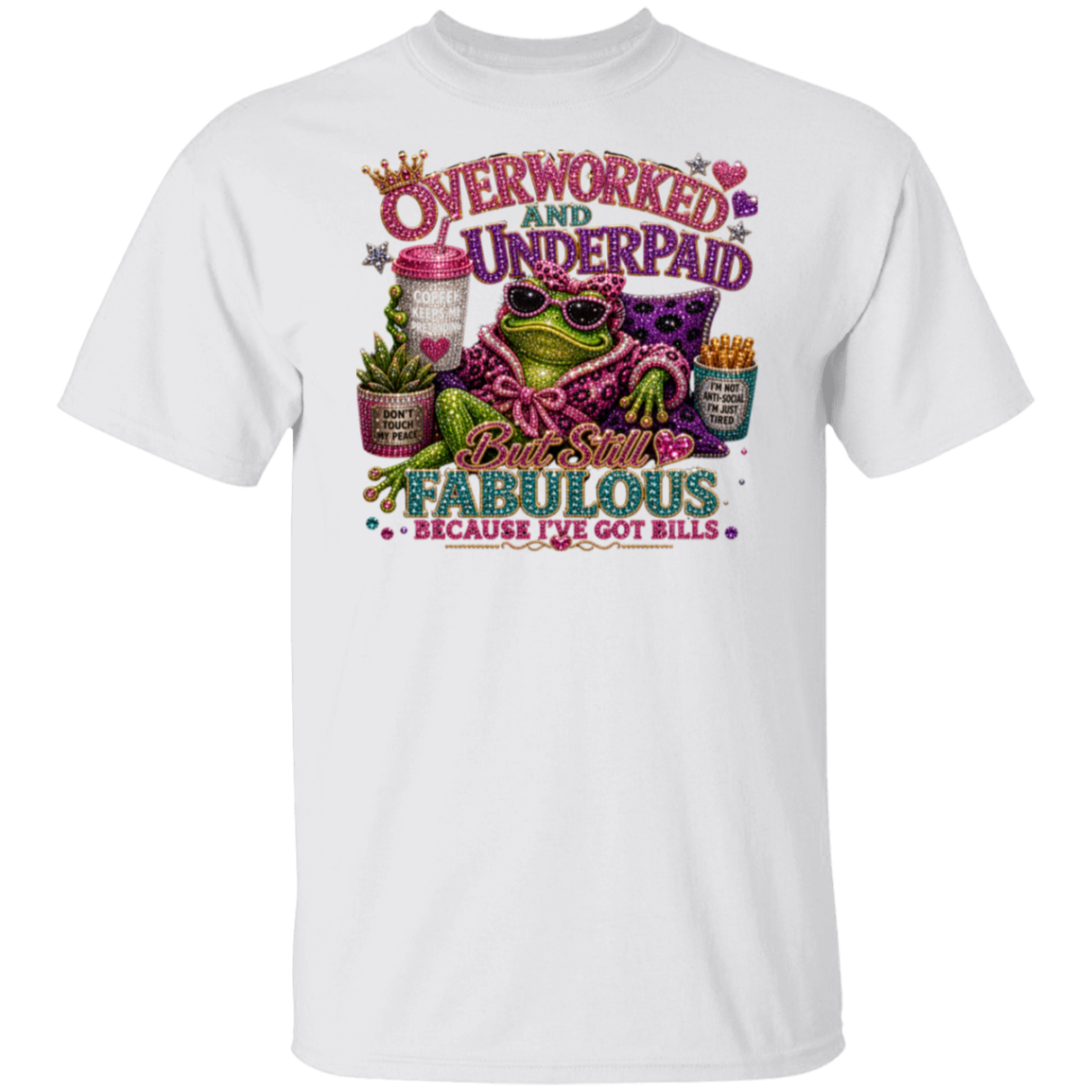 A white short-sleeve crewneck t-shirt featuring a colorful graphic print on the front. The graphic depicts a green frog wearing sunglasses and a purple patterned shirt, surrounded by text that reads 'OVERWORKED AND UNDERPAID' and 'But Still FABULOUS BECAUSE I'VE GOT BILLS'.
