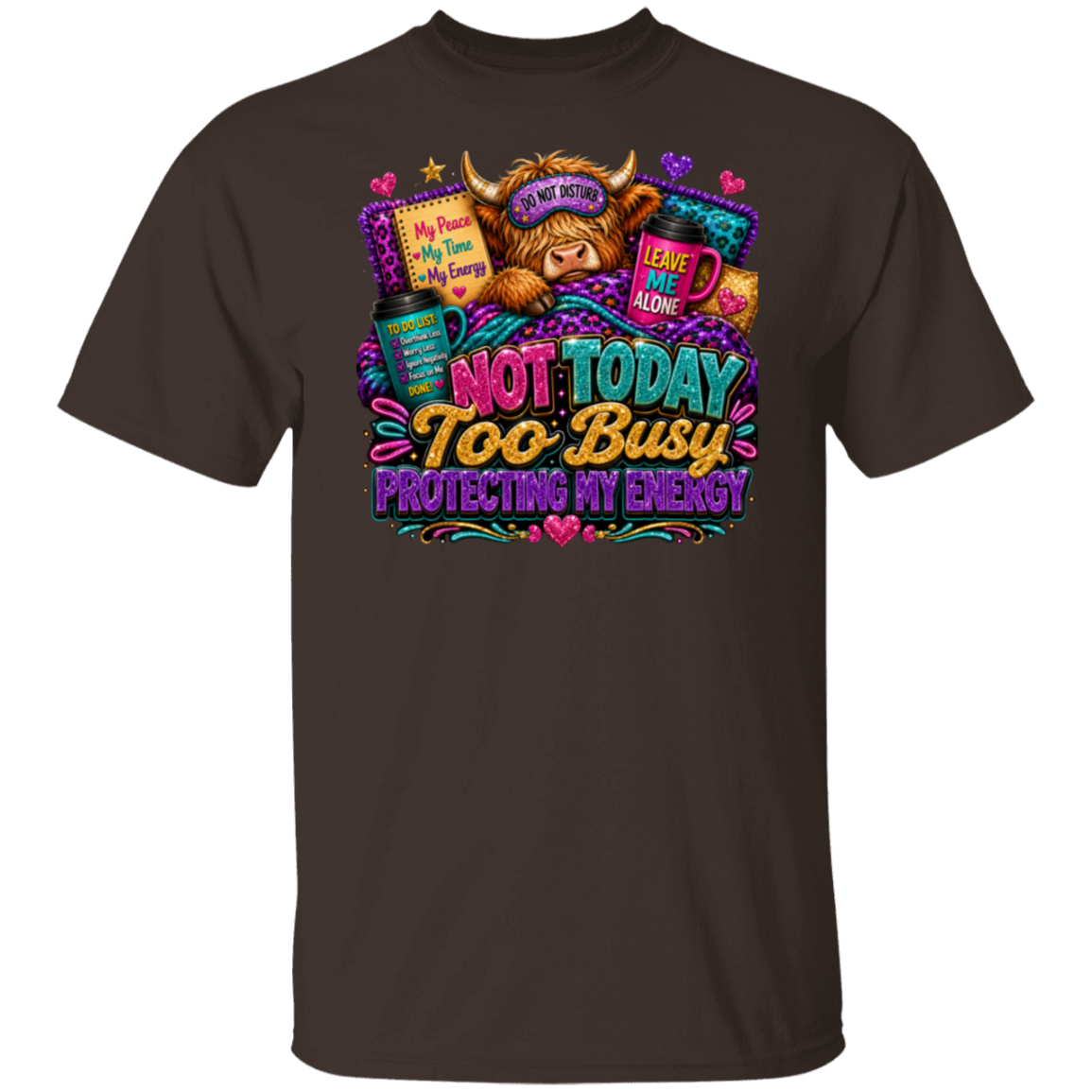 A dark chocolate short-sleeve crewneck t-shirt featuring a colorful graphic print of a cute highland cow wearing a sleep mask and surrounded by books, with the text 'NOT TODAY TOO BUSY PROTECTING MY ENERGY'.