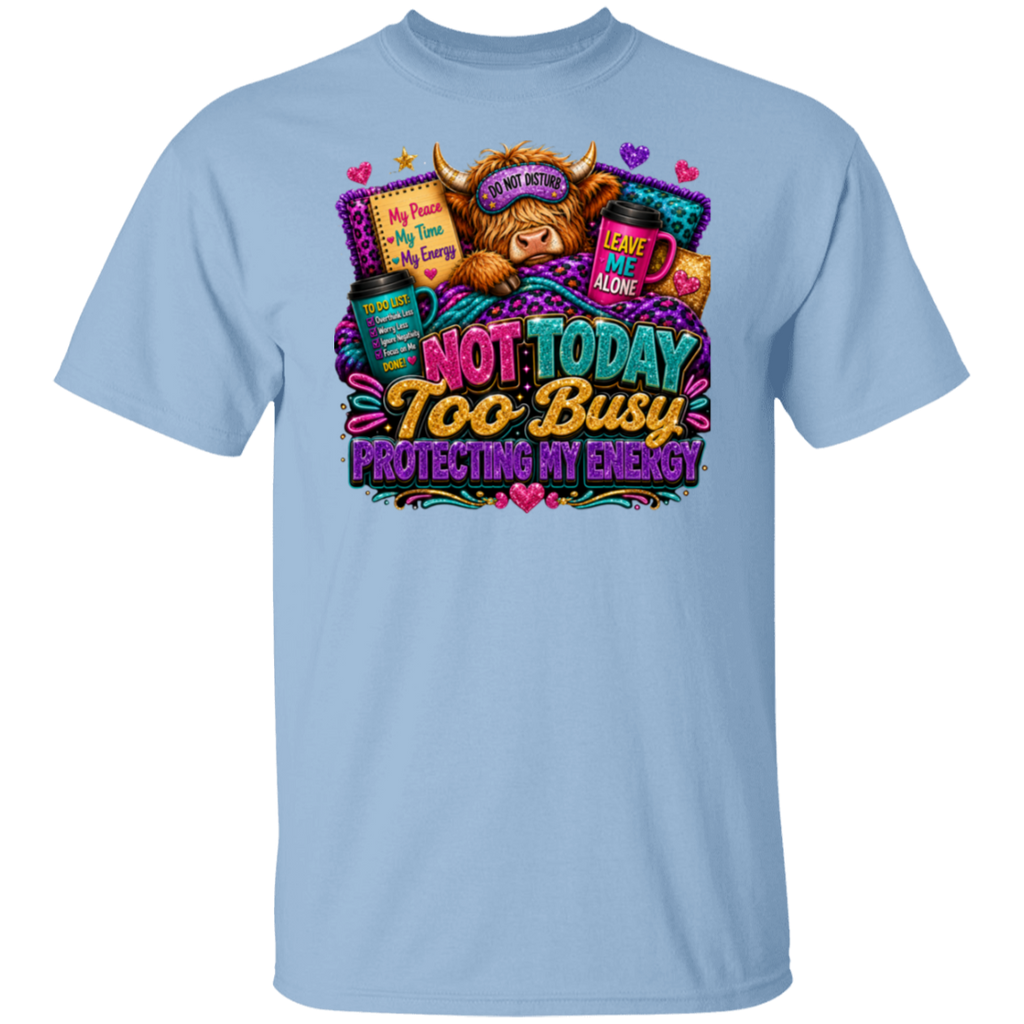 A light blue crewneck t-shirt featuring a colorful graphic print on the front. The graphic depicts a fluffy brown highland cow wearing a sleep mask that says 'I AM NOT A ZOMBIE' and a top hat reading 'MAD ALON SO DON'T WORRY'.