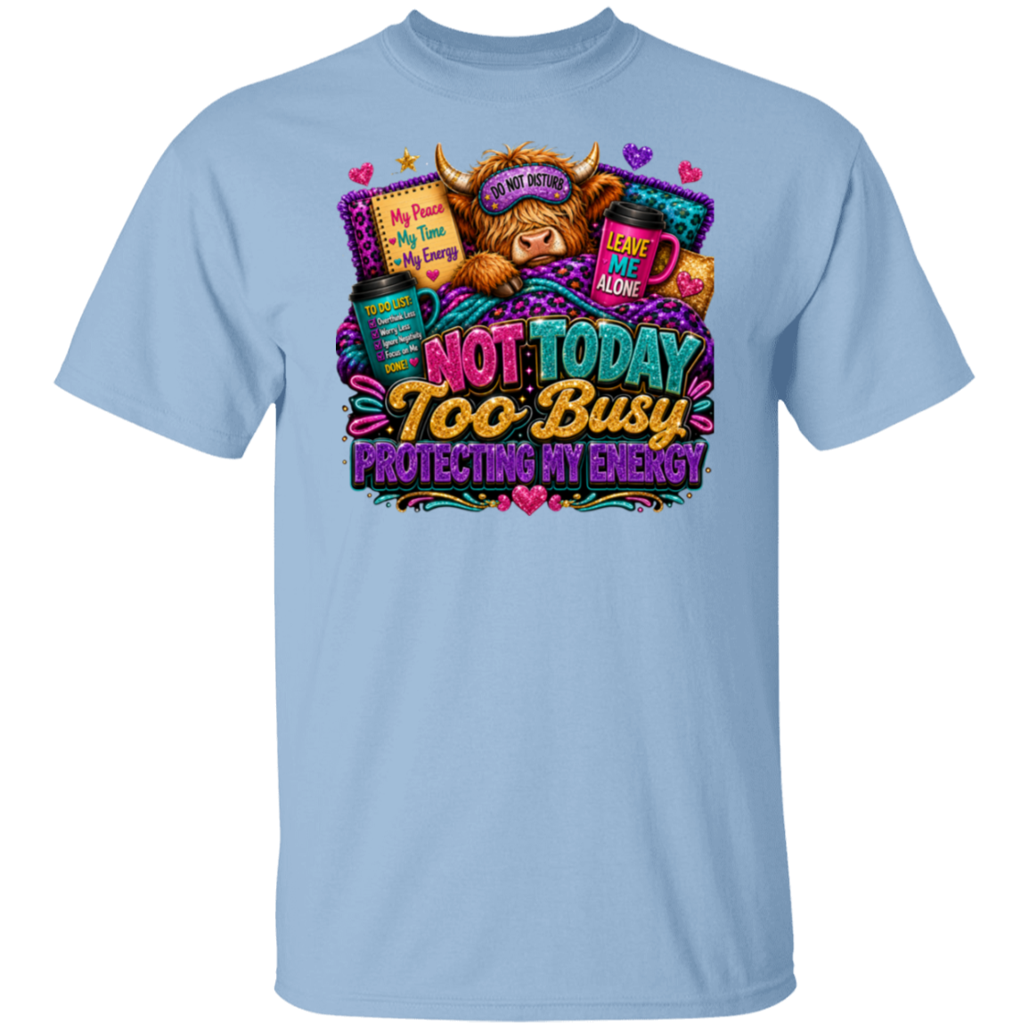 A light blue crewneck t-shirt featuring a colorful graphic print on the front. The graphic depicts a fluffy brown highland cow wearing a sleep mask that says 'I AM NOT A ZOMBIE' and a top hat reading 'MAD ALON SO DON'T WORRY'.