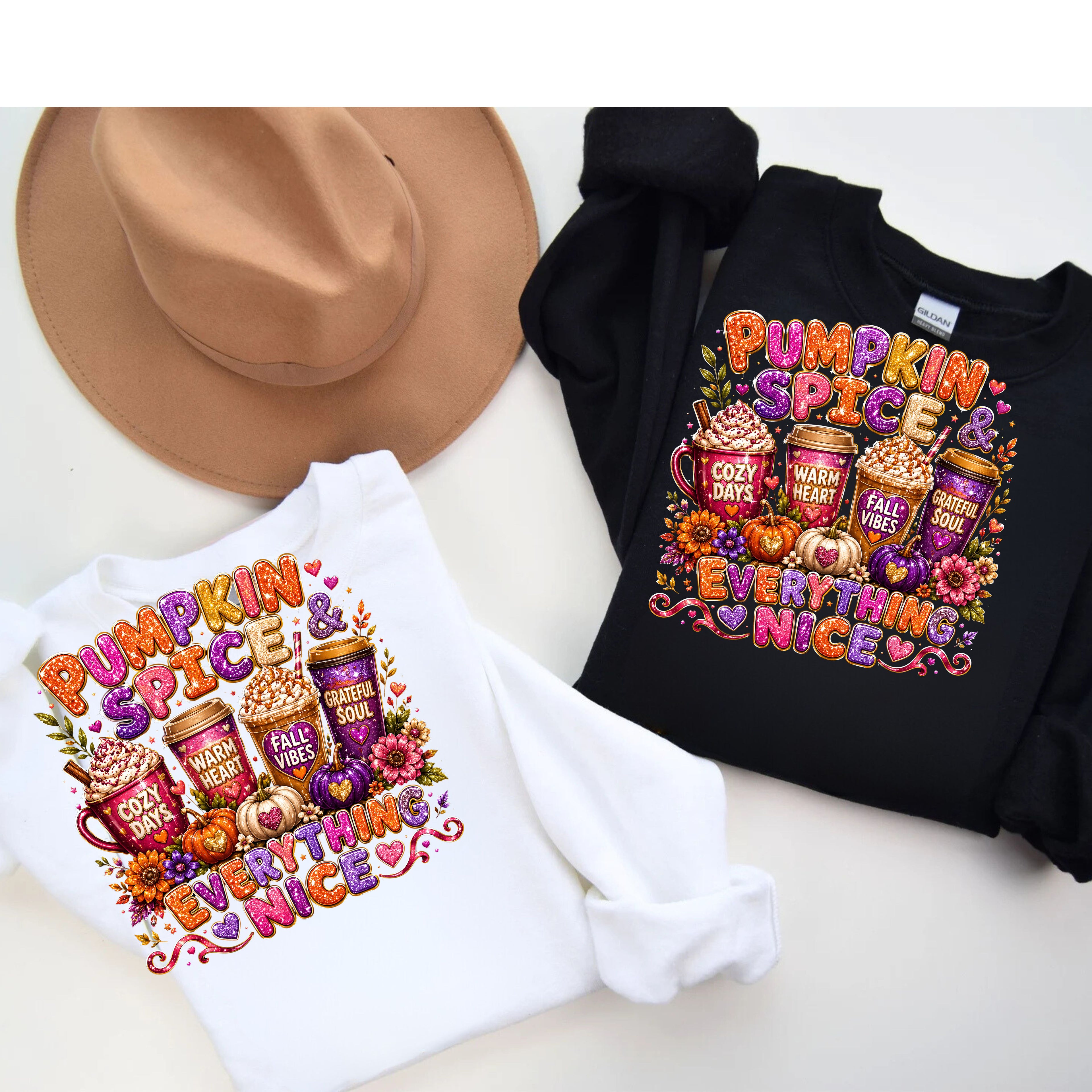 Two long-sleeve graphic sweatshirts, one white and one black, displayed flat with a tan wide-brim hat on a light beige background. The sweatshirts feature a colorful 'Pumpkin Spice & Everything Nice' graphic with coffee cups, pumpkins, and fall leaves.