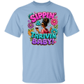 A light blue color short-sleeve crewneck t-shirt featuring a colorful graphic print of a raccoon surrounded by flowers and bold text that reads 'SIPPIN & THRIVIN BABY 100% COTTON LIGHT BLUE TSHIRT