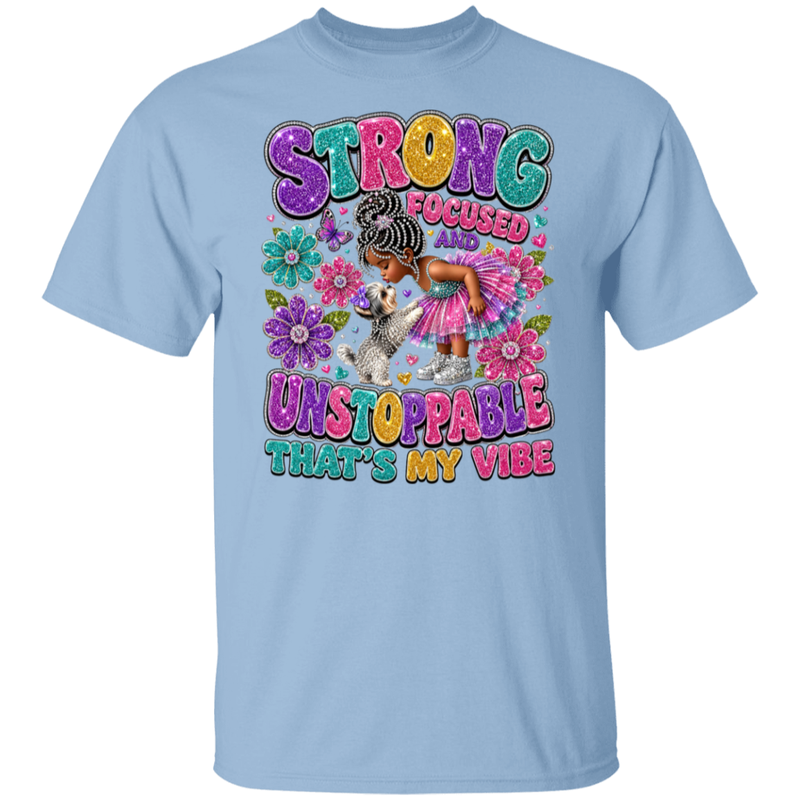 A light blue short-sleeve crewneck t-shirt featuring a colorful graphic print on the front. The graphic displays the text 'STRONG FOCUSED UNSTOPPABLE THAT'S MY VIBE' in a playful, multi-colored bubble font, accompanied by an illustration of a woman with braided hair in a pink dress and a small white dog surrounded by flowers.