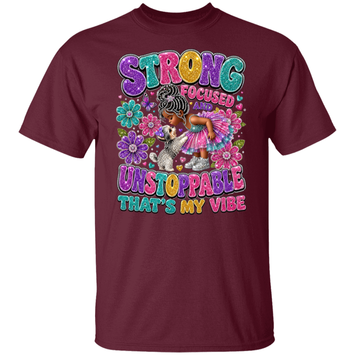 A maroon color short-sleeve crewneck t-shirt featuring a colorful graphic print on the front. The graphic displays a young girl with braided hair in a pink dress surrounded by flowers, with the text 'STRONG FOCUSED AND UNSTOPPABLE THAT'S MY VIBE' in a playful, multi-colored font.