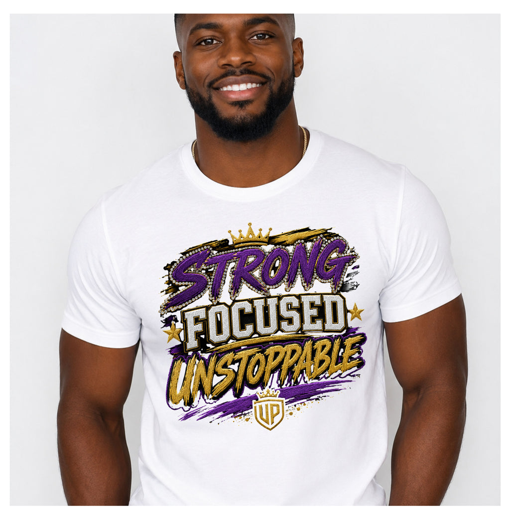 A man wearing a white short-sleeve graphic t-shirt with the text 'STRONG FOCUSED UNSTOPPABLE' in purple, gold, and black stylized lettering, set against a plain light gray background.