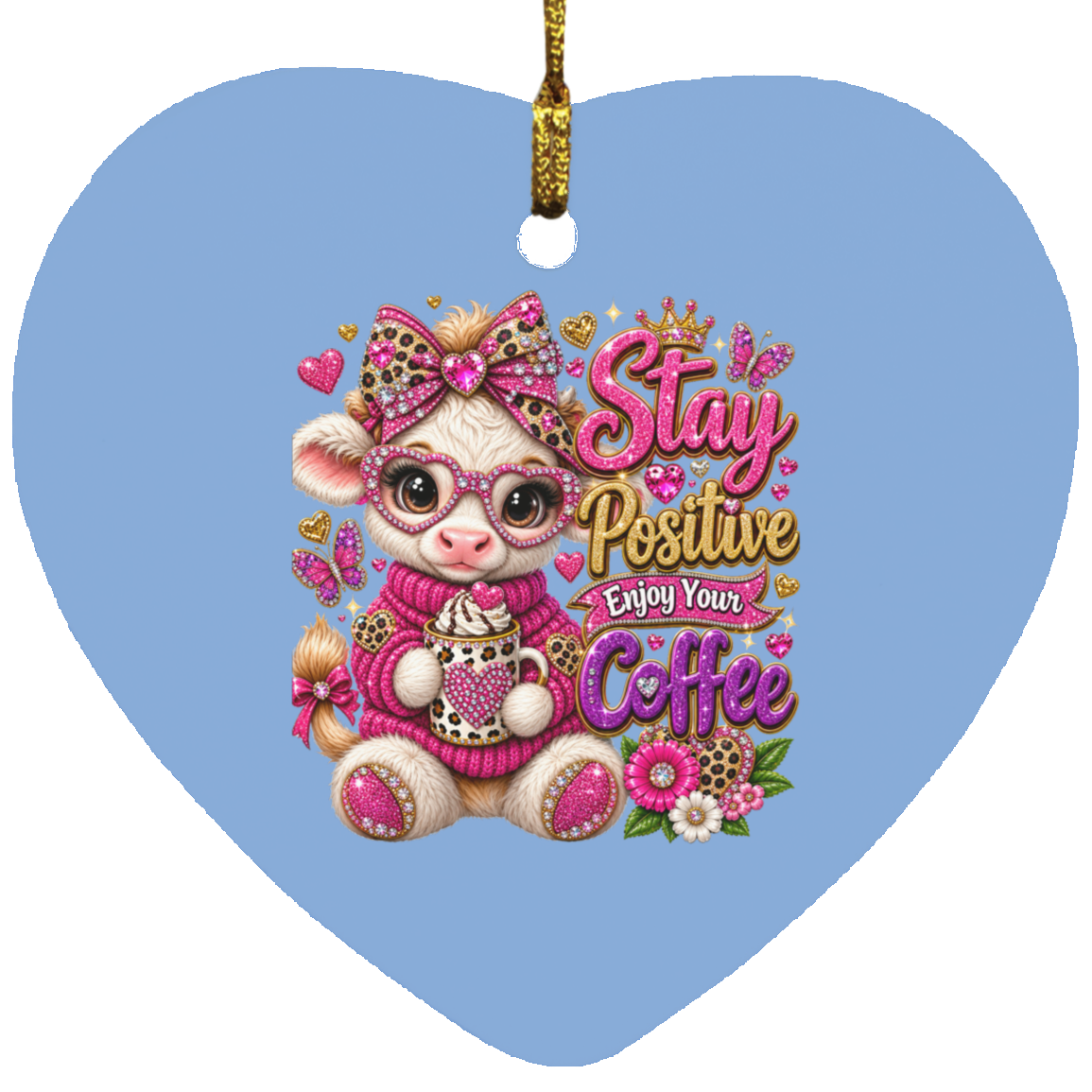 Heart-shaped Columbia blue ceramic ornament featuring a cute cartoon cow character wearing pink glasses, a pink bow, and a pink sweater while holding a cup of coffee. The ornament has a gold hanging string and the text 'Stay Positive Enjoy Your Coffee' in pink and gold lettering.