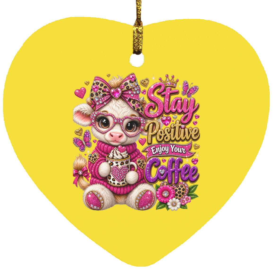 A heart-shaped yellow ornament featuring a cute cartoon cow wearing pink glasses, a pink bow, and a pink sweater while holding a coffee cup. The text reads 'Stay Positive Enjoy Your Coffee' in pink and gold lettering with small hearts, flowers, and glitter details.