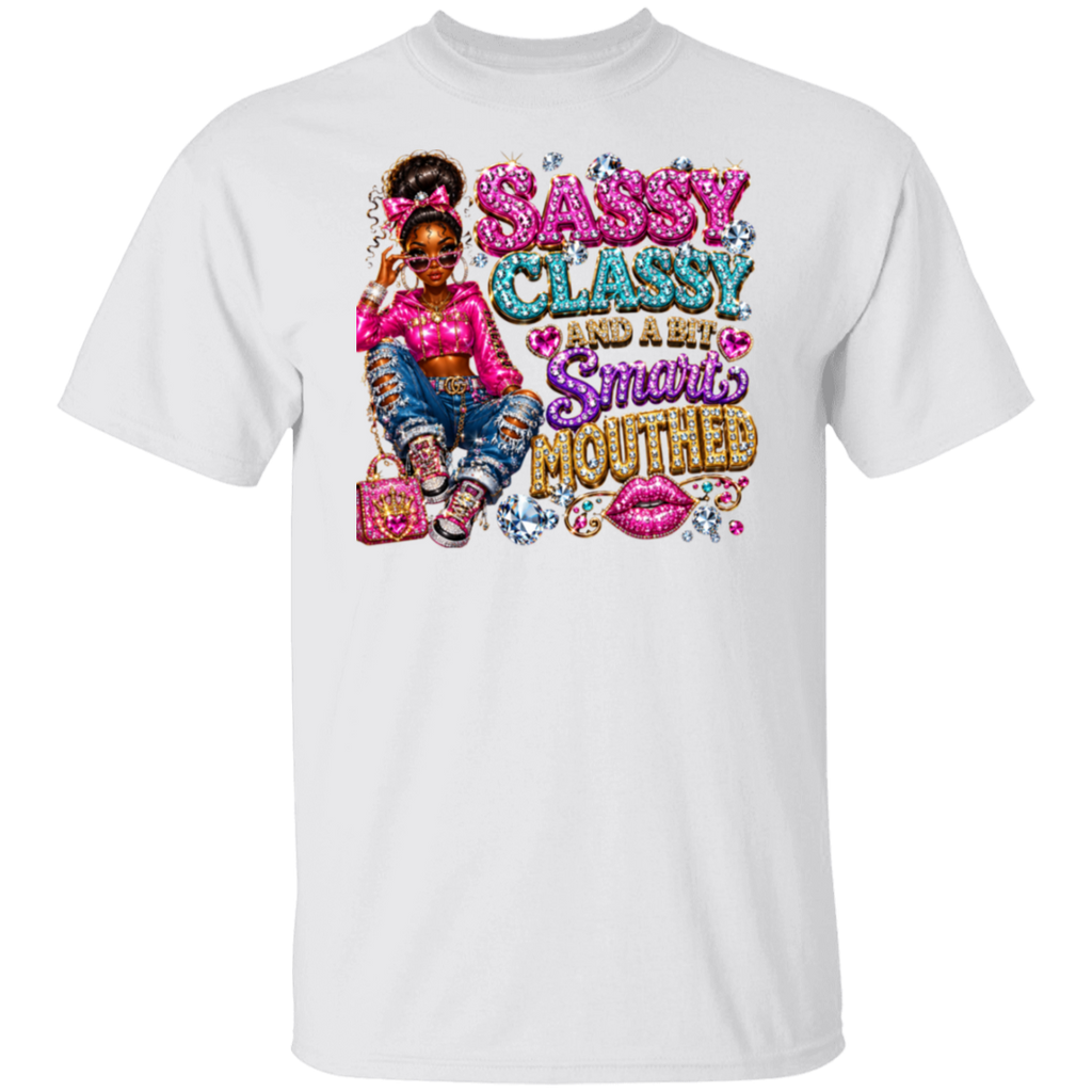 A white short-sleeve crewneck t-shirt featuring a colorful graphic print on the front. The graphic depicts a young girl with braided hair wearing a pink top and ripped blue jeans, sitting next to a pink purse, with the text 'SASSY CLASSY AND A BIT Smarts MOUTHED' in glittery pink, blue, and gold lettering.