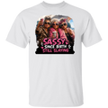 A white short-sleeve crewneck t-shirt featuring a colorful graphic print of three elderly women taking a selfie with the text 'SASSY SINCE BIRTH STILL SLAYING' in pink and white lettering.