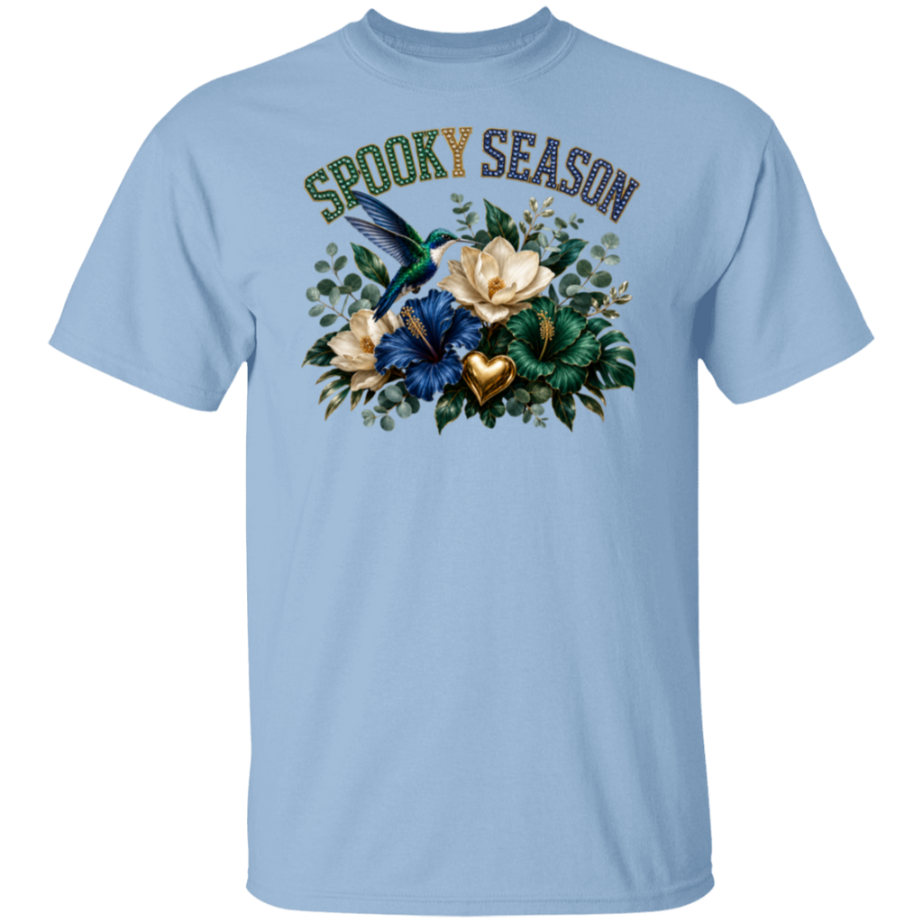 A light blue crewneck t-shirt featuring a 'Spooky Season' graphic on the chest with a hummingbird, flowers, and a gold heart.
