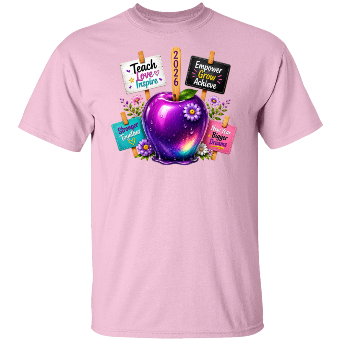 A light pink short-sleeve crewneck t-shirt featuring a colorful graphic of a glowing purple galaxy apple with flowers, surrounded by motivational signs that say 'Teach Love Inspire', '2026', 'Empower Grow Achieve', 'Shining Together', and 'Helper Bigger Helper'.