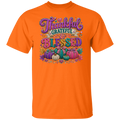 A safety orange color short-sleeve crewneck t-shirt featuring a colorful graphic on the front with the words 'Thankful Grateful Blessed' in stylized purple and multicolor lettering above a decorative pumpkin illustration. 