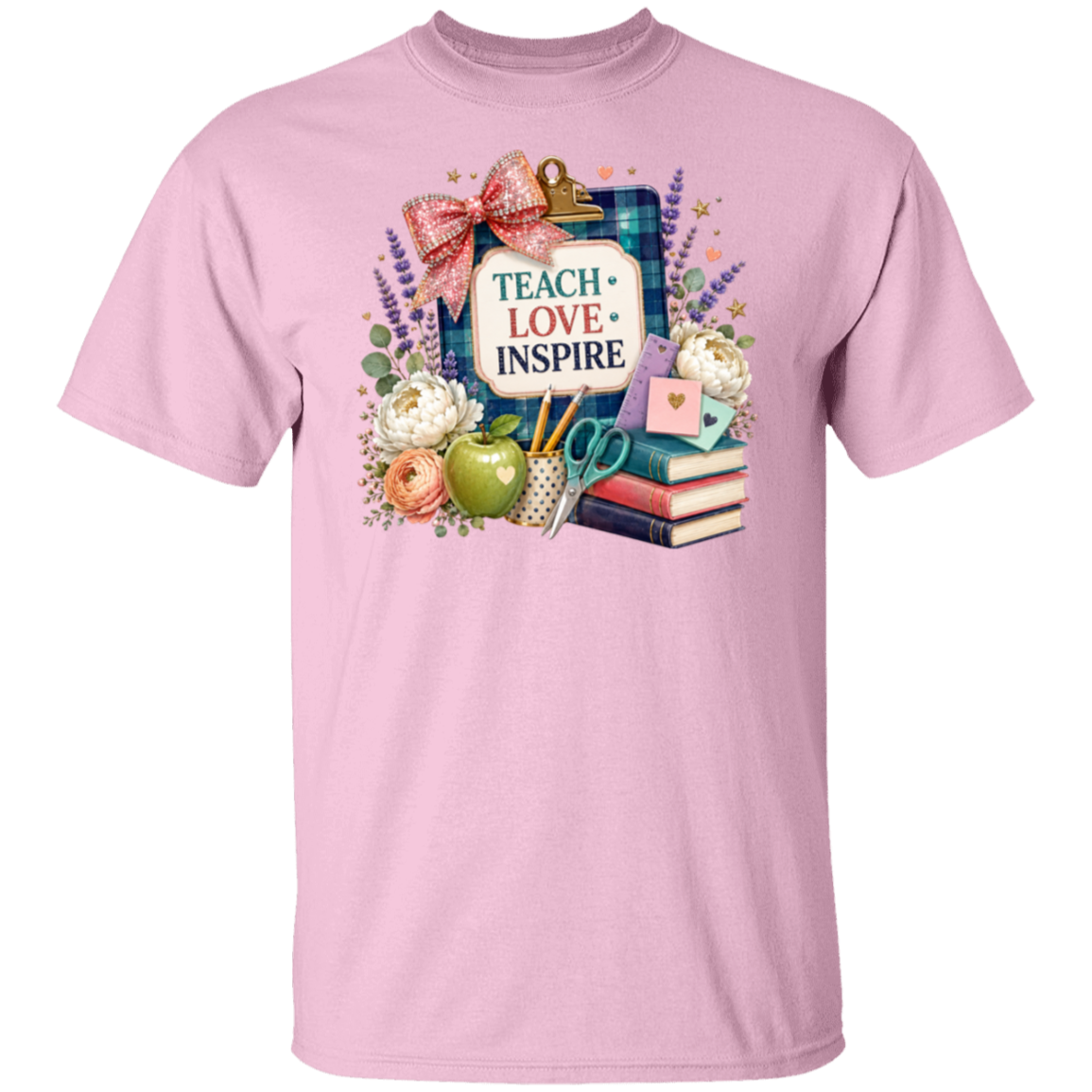 A light pink short-sleeve crewneck t-shirt featuring a colorful graphic print on the front. The graphic depicts a clipboard with a plaid background, a pink bow, the words 'TEACH LOVE INSPIRE' in a white sign, a green apple, books, flowers, and lavender.
