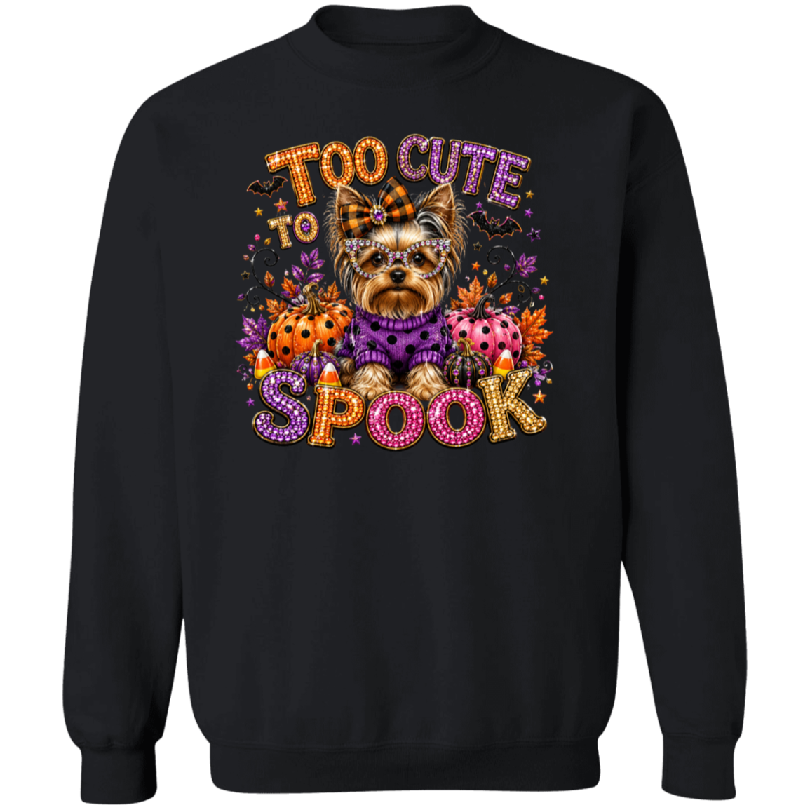 A black crewneck sweatshirt featuring a colorful graphic print of a cute Yorkshire Terrier dressed in a purple sweater, surrounded by Halloween elements like candy corn, ladybugs, and the text 'TOO CUTE TO SPOOK' in a glittery, multicolored font.