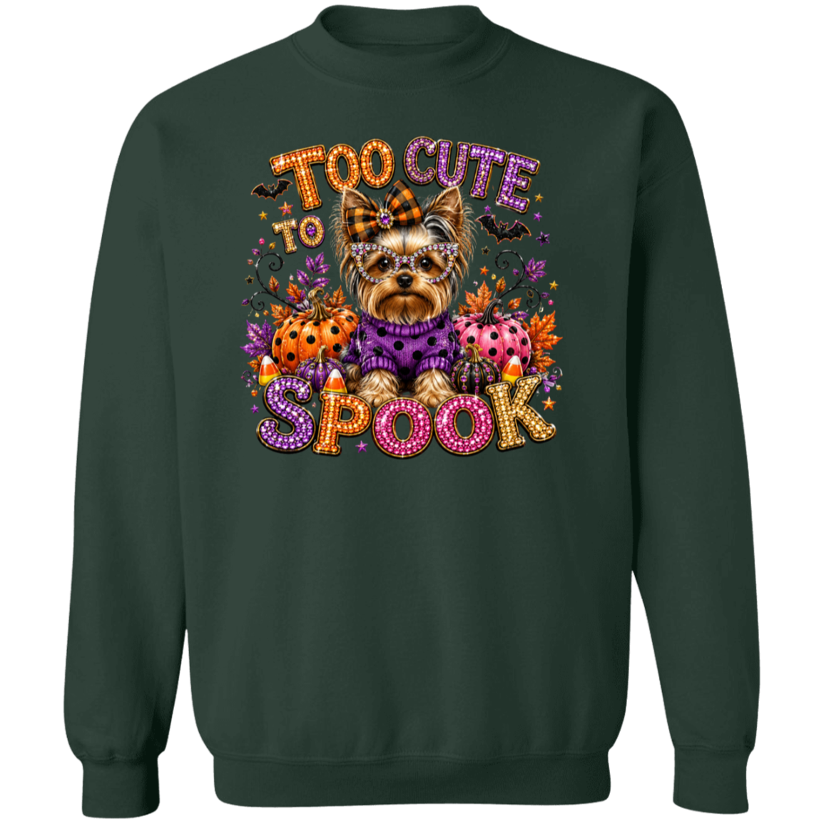 A forest green crewneck sweatshirt featuring a colorful graphic of a Yorkshire Terrier dog in a purple sweater surrounded by Halloween elements, with the text 'TOO CUTE TO SPOOK' in a glittery, multicolored font.