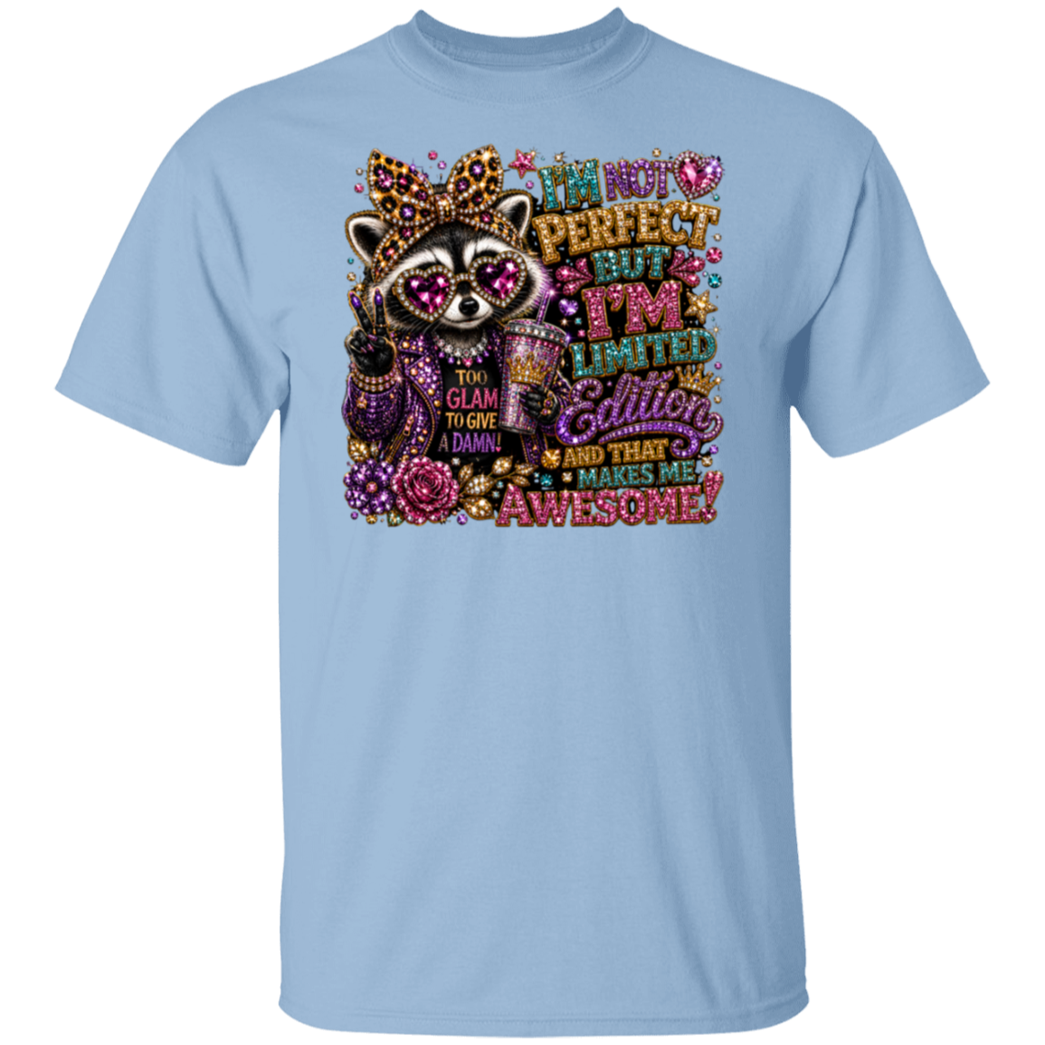 A light blue short-sleeve crewneck t-shirt featuring a colorful graphic of a raccoon wearing a crown and sunglasses, surrounded by glittery text that reads 'I'm not perfect but I'm limited edition glitter and that makes me awesome!'.