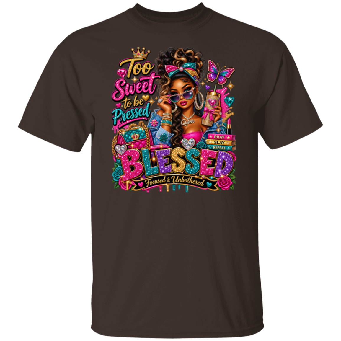 A dark chocolate short-sleeve t-shirt with a colorful graphic print on the front. The graphic features a stylized illustration of a woman with sunglasses, a butterfly, and the text 'Too Sweet to be Pressed BLESSED Focused & Unburdened'.