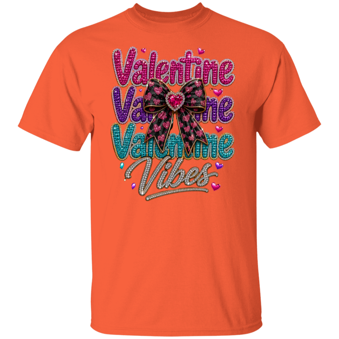 An orange short-sleeve crewneck t-shirt featuring a colorful graphic on the front that reads 'Valentine Valentine Valentine Vibes' in pink, purple, and teal glitter-style lettering, decorated with a black and pink bow and small hearts.