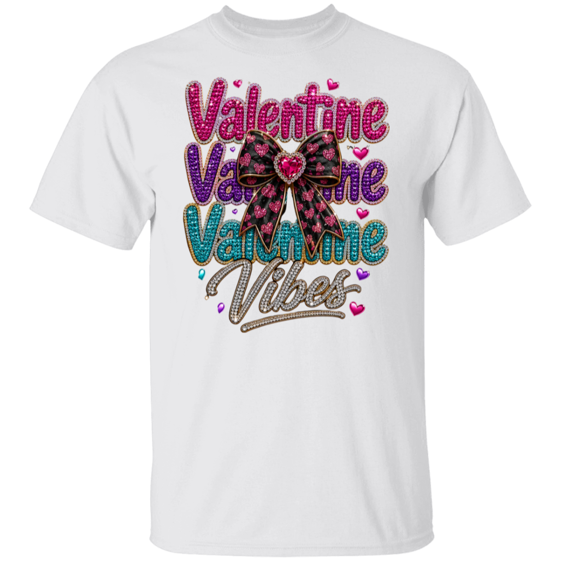 A white short-sleeve crewneck t-shirt featuring a colorful graphic on the front that reads 'Valentine Vibes' in pink, purple, and teal glitter-style lettering, accented by a pink and black plaid bow with a red heart in the center.